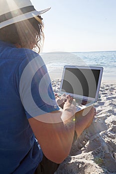 Man using laptop on the beach