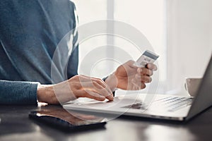 Man using laptop computer and holding credit card. Young businessman or entrepreneur working at home