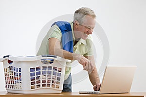 Man Using Laptop While Doing the Laundry