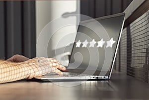 Man using laptop for giving positive feedback. Five star rating of service quality, application, film. Excellent