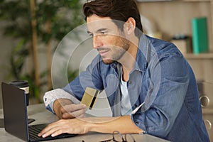 Man using laptop and holding bankcard photo