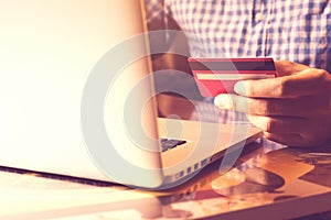 Man using laptop and holding credit card with online shopping or internet banking concept.