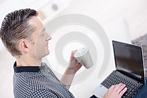 man using laptop and holding cup