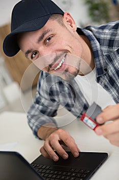 man using laptop and holding ink cartridge