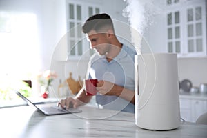 Man using laptop in kitchen with air humidifier