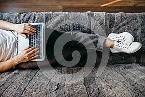 Man is using a laptop while lying on sofa in living room