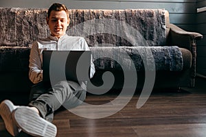 Man is using a laptop while lying on sofa in living room