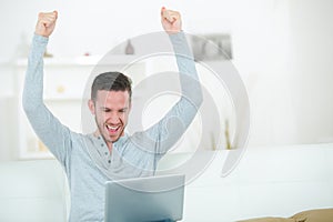 Man using laptop making triumphant gesture