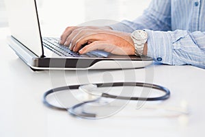 Man using laptop near a stethoscope on desk