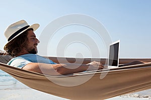 Man using laptop while relaxing on hammock