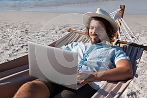 Man using laptop while relaxing on hammock