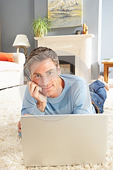 Man Using Laptop Relaxing Laying On Rug At Home