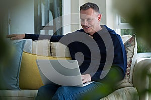 Man using laptop on sofa in living room