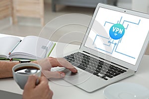 Man using laptop with switched on VPN at desk indoors, closeup