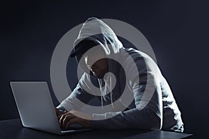 Man using laptop at table on dark background