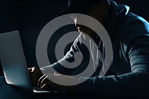 Man using laptop at table on dark. Criminal activity
