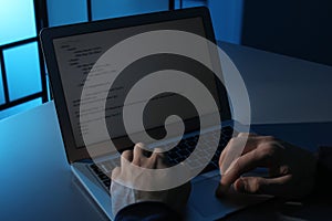 Man using laptop at table in dark room, closeup