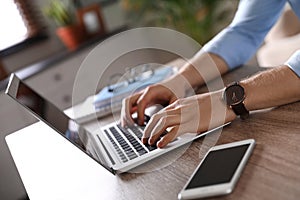 Man using laptop at table indoors