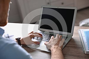 Man using laptop at table indoors. Space for text