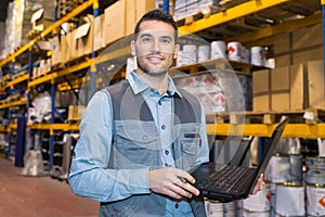 man using laptop in warehouse