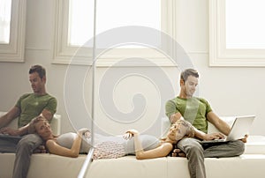 Man Using Laptop With Woman Lying On His Lap