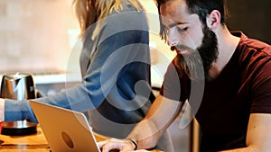 Man using laptop while woman preparing coffee 4k