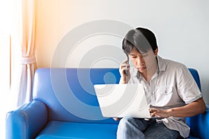 A man using laptop for works and online activities while talking on mobile phone and sitting for business discussion