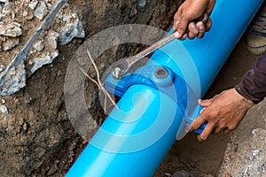 Man using a large wrench on water pipes. Construction site with new Water Pipes in the ground. Sewer pipes to repair or restore in
