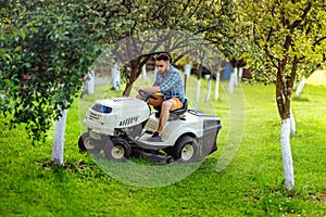 Man using lawn tractor for mowing grass in garden.