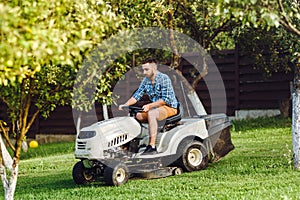 Man using lawn tractor for mowing grass in household garde