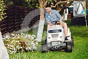 Man using lawn tractor for mowing grass in household garden