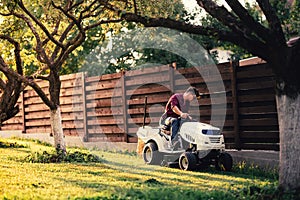 Man using lawn tractor for mowing grass. Landscaping works with professional tools