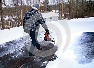 Man using leaf blower to clear snow from driveway