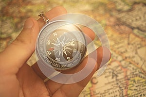 Man using magnetic compass on a world map. Travel, tourism and exploration concept background photo