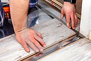 Man using measuring elbow and pencil while installing new wooden laminate flooring at home.