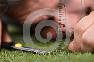 Man Using Measuring Scale While Cutting Grass