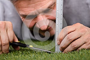 Man Using Measuring Scale While Cutting Grass