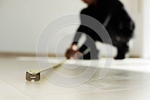 Man using a measuring tape on a tiled floor photo