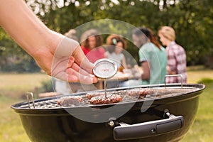 Man using meat thermometer while barbecuing