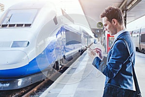 Man using mobile application on his smartphone at train station