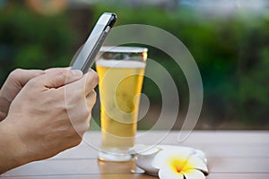 Man using mobile during happy time relax in restaurant with softdrink and green garden background