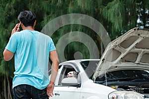 Man using mobile phone and calling for help while the car broken