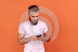 Man using mobile phone with calm expression, addicted to smartphone, texting in social network.