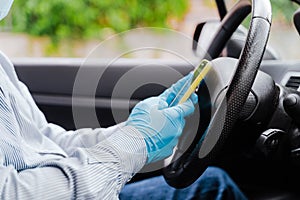 Man using mobile phone in a car wearing protective mask and gloves during pandemic coronacirus covid-19