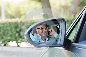 Man using mobile phone while driving car to work reflection in side mirror