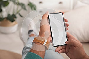 Man using mobile phone with empty screen indoors, closeup