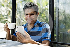 Man using mobile phone while having hot drink