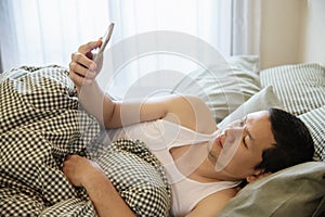 Man using mobile phone while wake up on bed in the morning