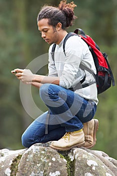 Man Using Mobile Phone Whilst Hiking In Countryside