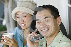 Man using mobile phone and woman with drink